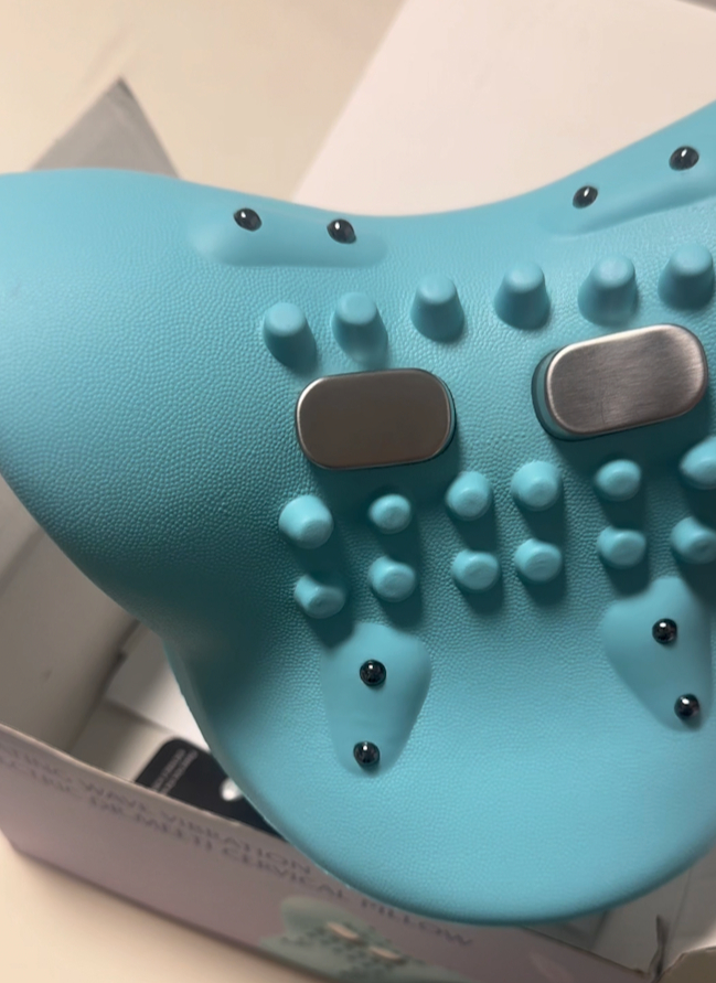 A close-up of a light blue textured massage device with nubs and metallic pads.