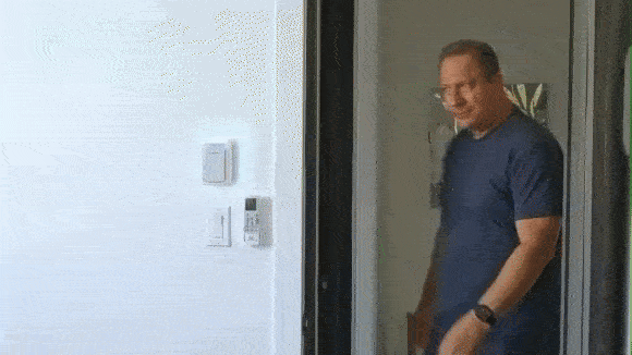 Man in blue shirt entering a room through a door.