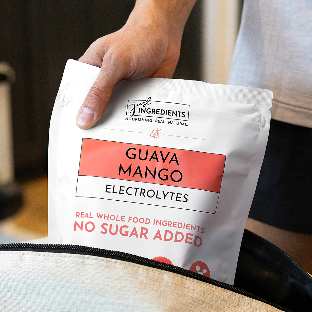 Hand holding a bag of guava mango electrolytes with no sugar added.