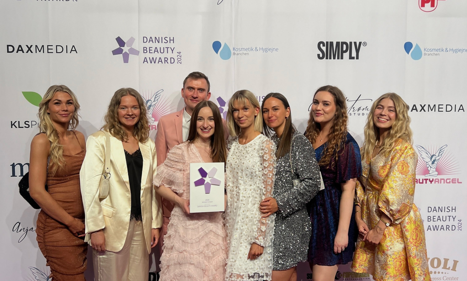 A group of eight people smiling for a photo while holding an award at the Danish Beauty Award 2024.