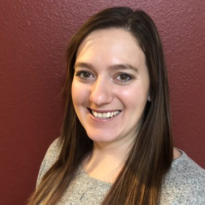 Person smiling in front of a red wall.