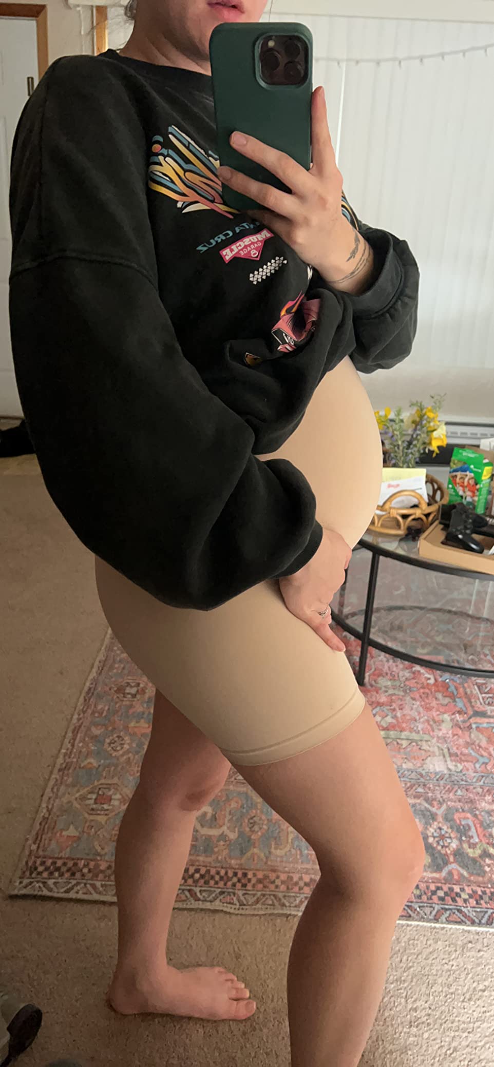 Person taking a mirror selfie wearing a sweatshirt and beige shorts.