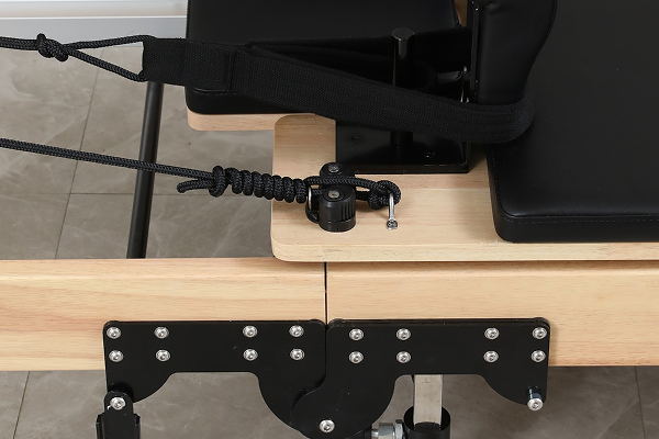 Close-up of wooden exercise equipment with black straps and metal fixtures.