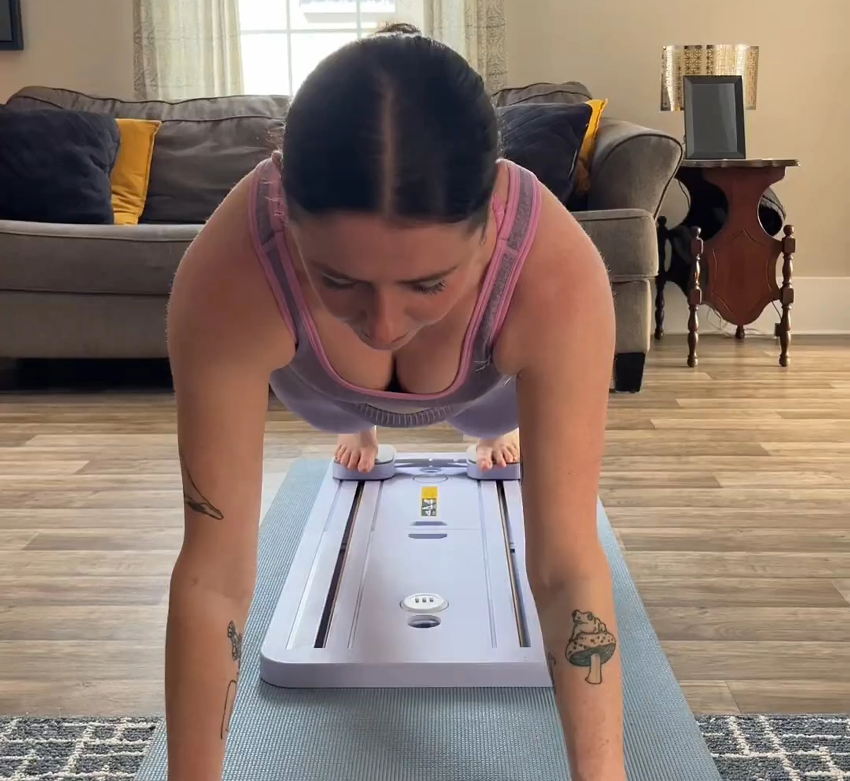A woman holds a plank position on a yoga mat with her feet on an exercise board.