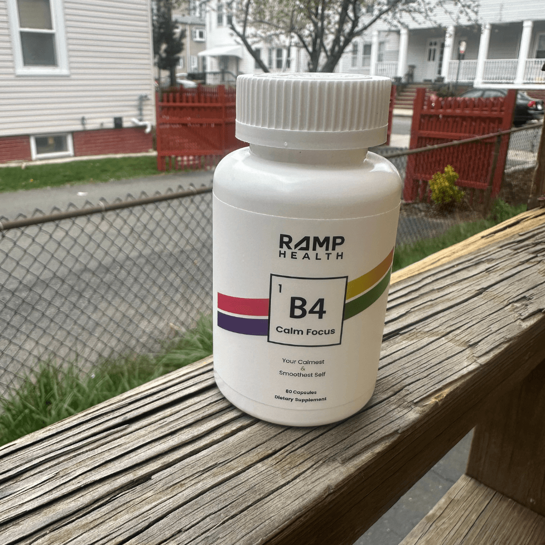 A bottle labeled 'B4 Calm Focus' on a wooden railing outdoors.
