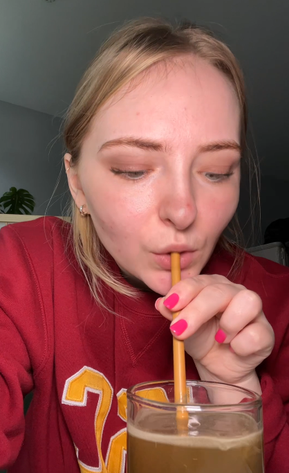 Person in a red sweatshirt drinking from a glass with a straw.