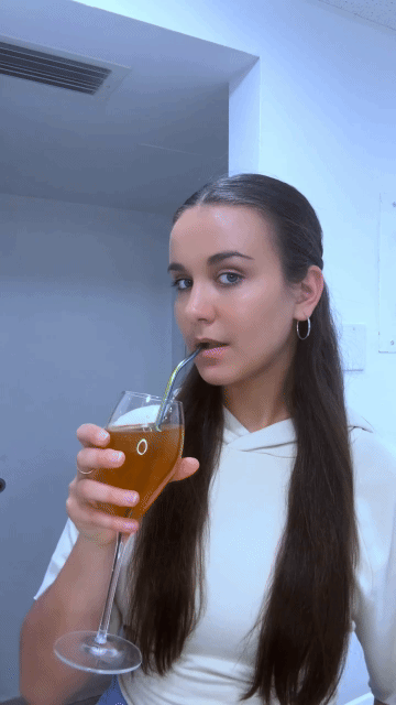 Person drinking from a wine glass with a straw.