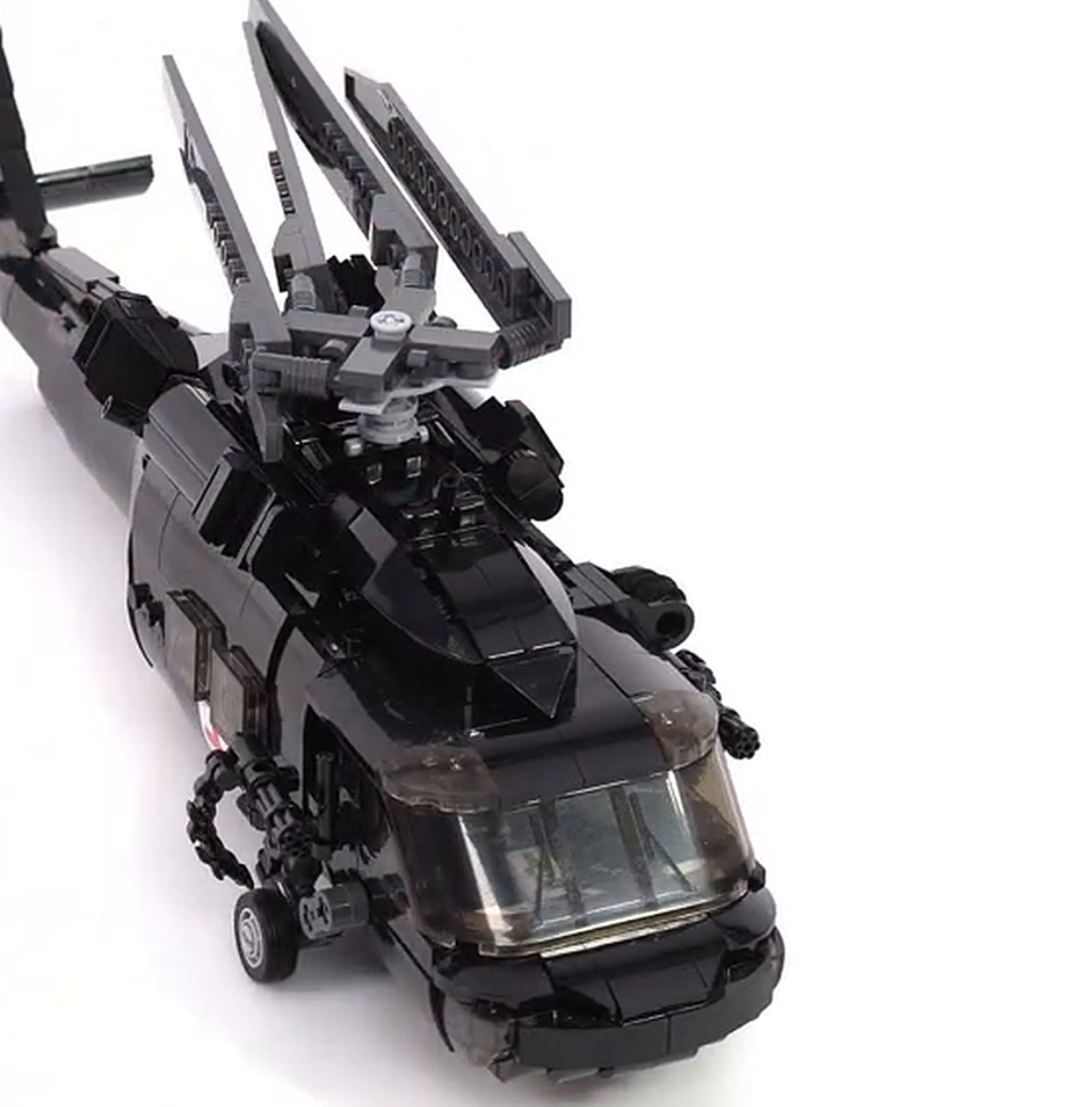 A close-up of a black toy helicopter made of building blocks against a white background.