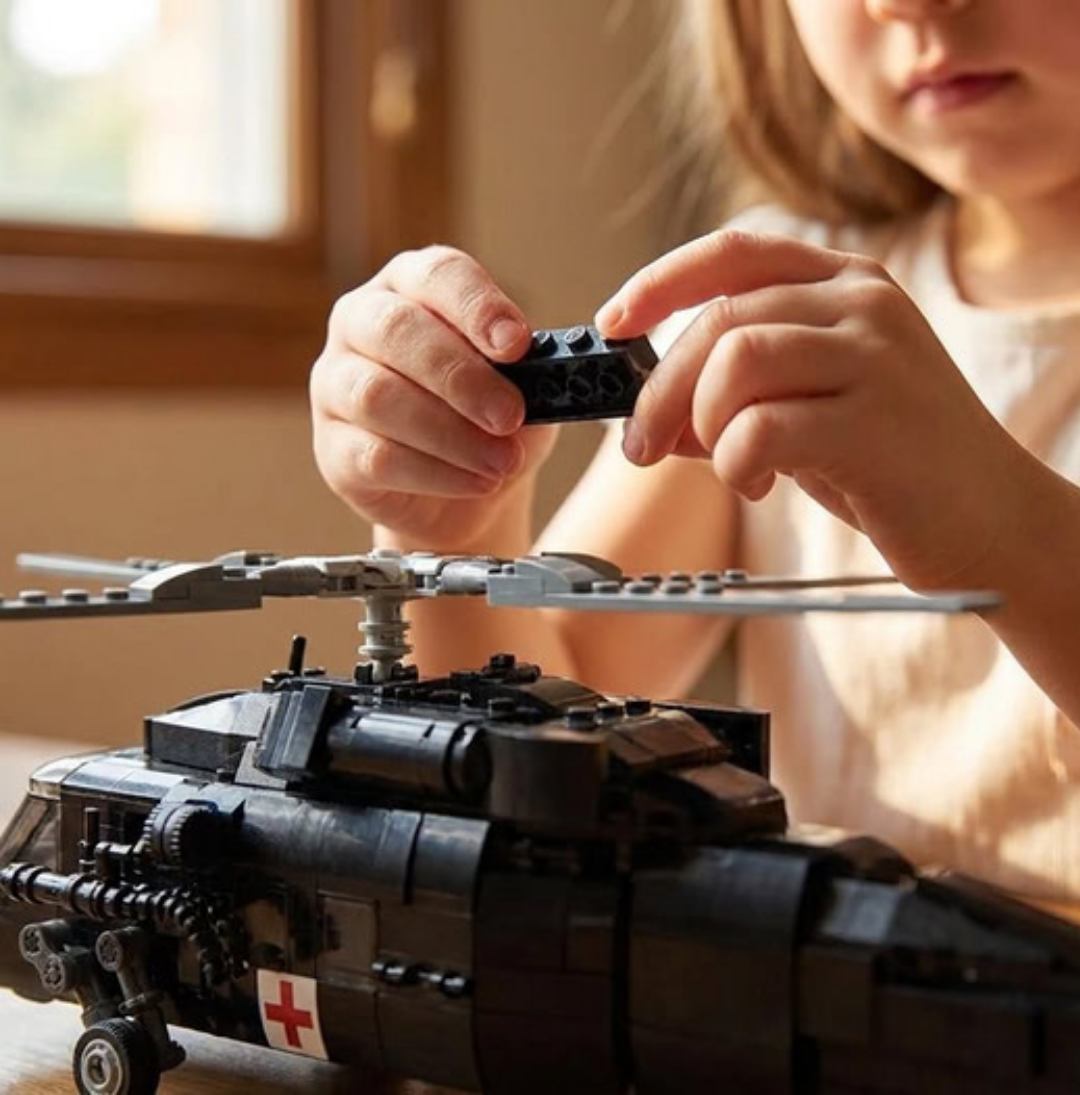 A child assembles a black toy helicopter made from building blocks.