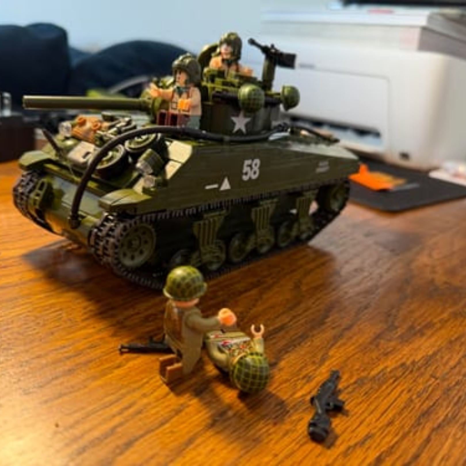 A toy tank and soldier figures made from building blocks on a wooden desk.
