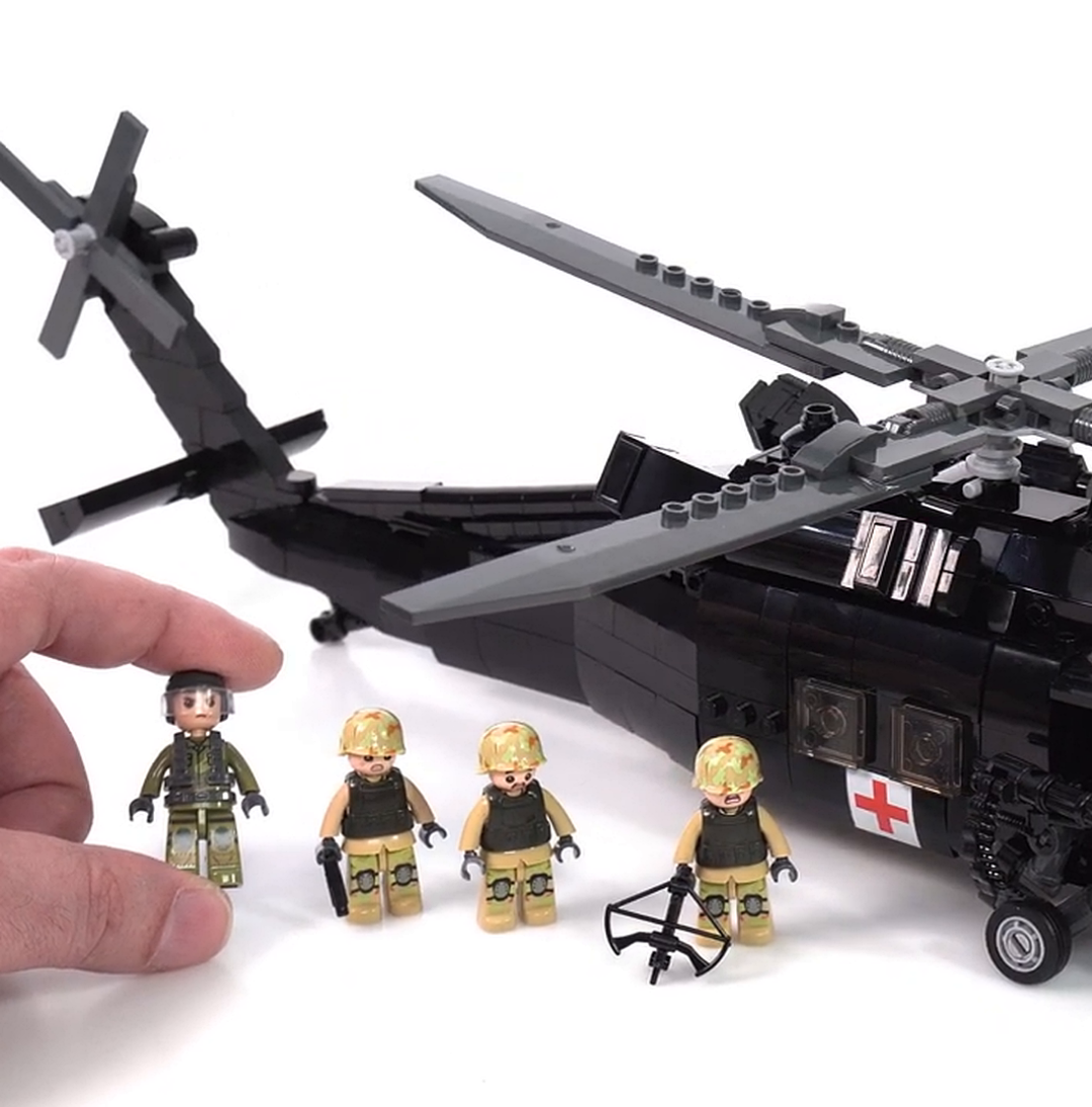 A black toy helicopter made of building blocks with four small soldier figures in front of it.