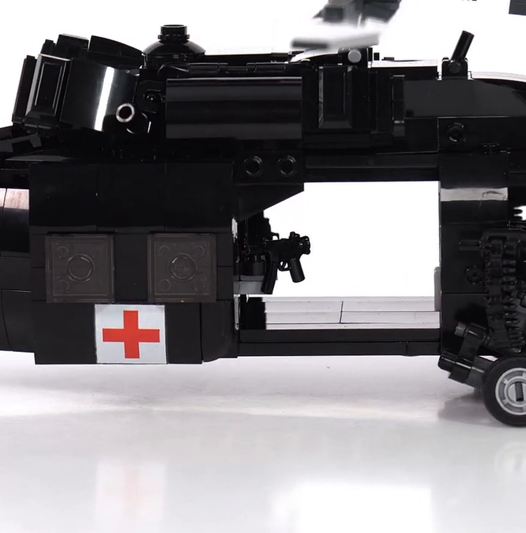 A close-up of a black toy helicopter made of building blocks, with a red cross symbol.