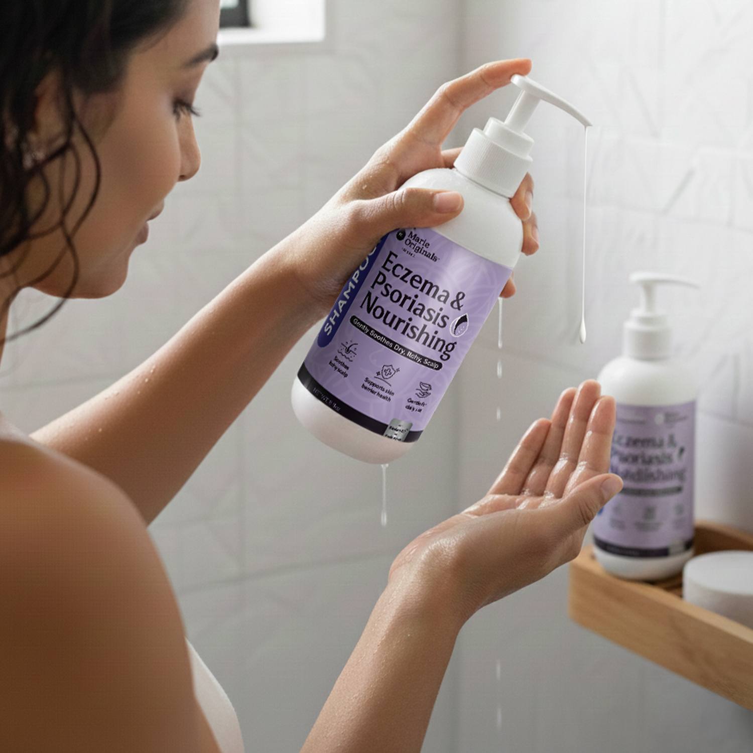 A woman dispenses Eczema & Psoriasis Nourishing shampoo from a pump bottle into her hand.