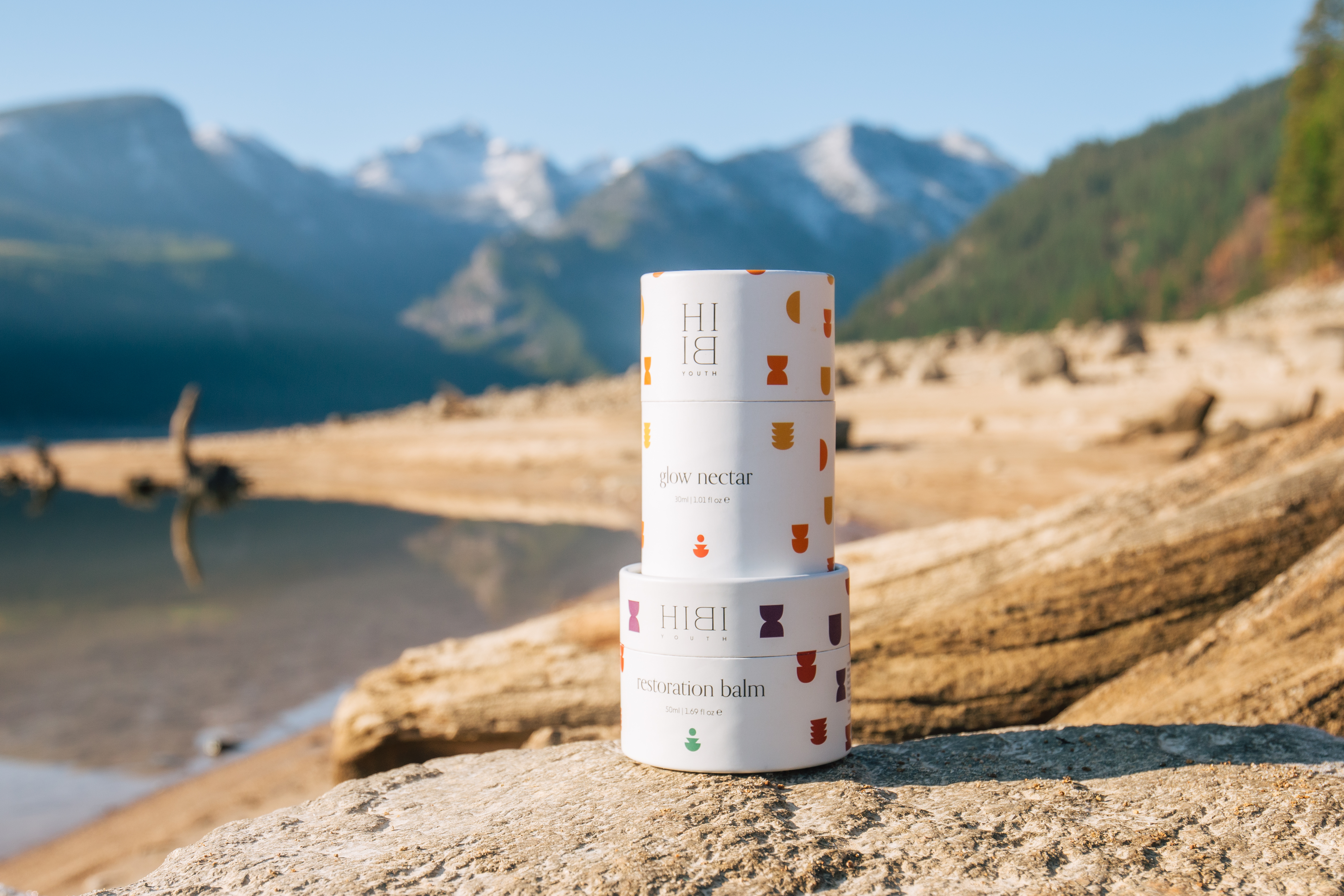 Skincare products on a rock with mountains in the background.