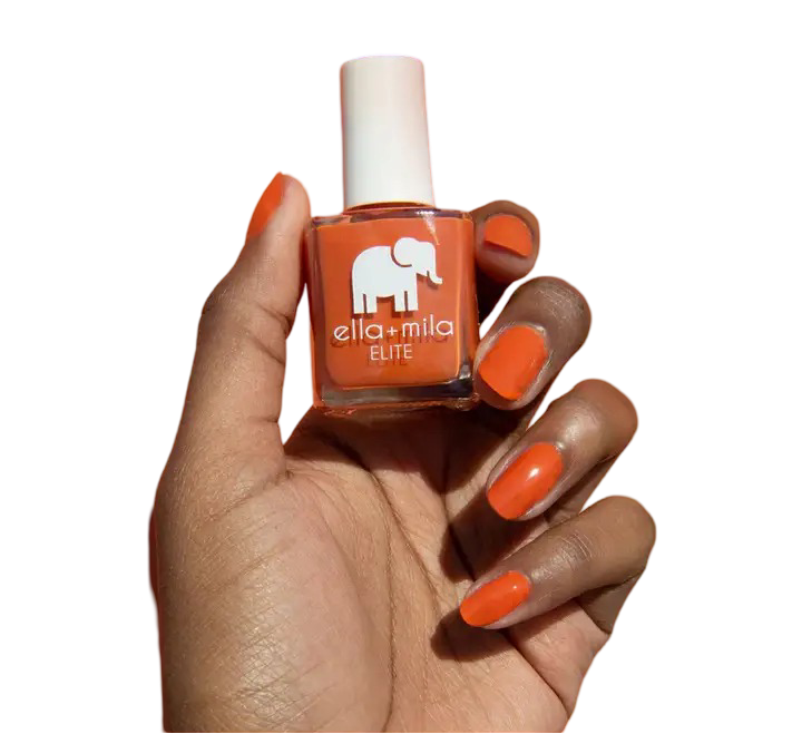 Hand holding orange nail polish bottle with matching painted nails.