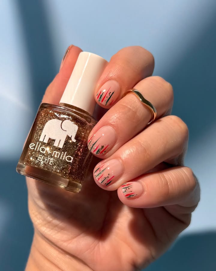 Hand holding glitter nail polish bottle with painted nails.