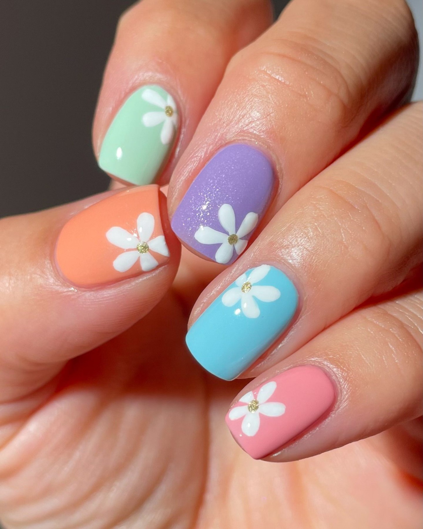Colorful nails with daisy designs on each finger.