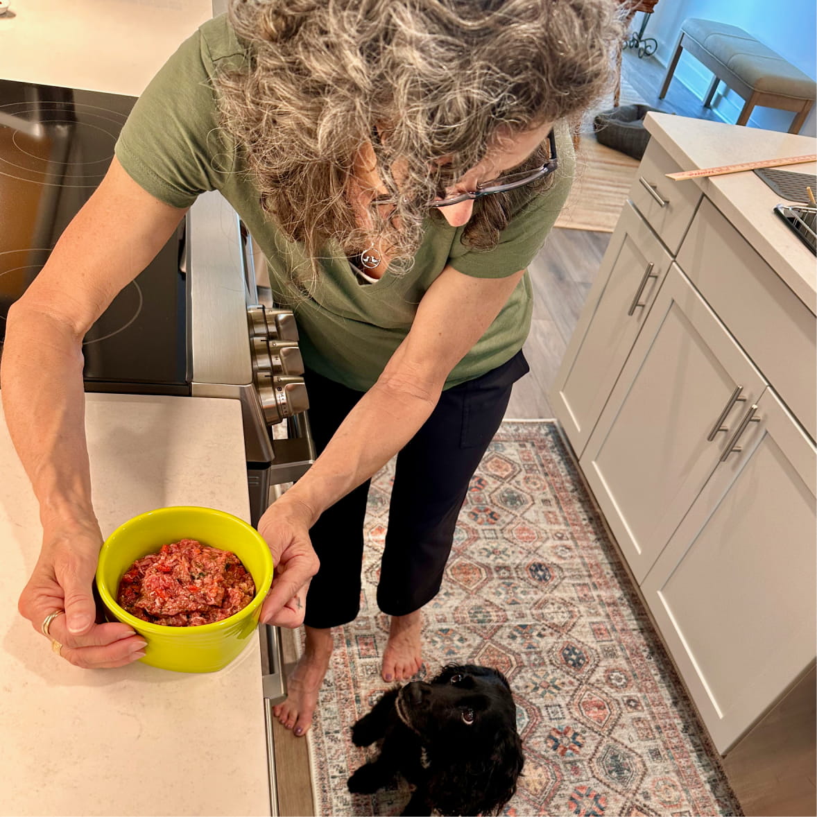 Woman feeding dog Rebel Raw food in kitchen