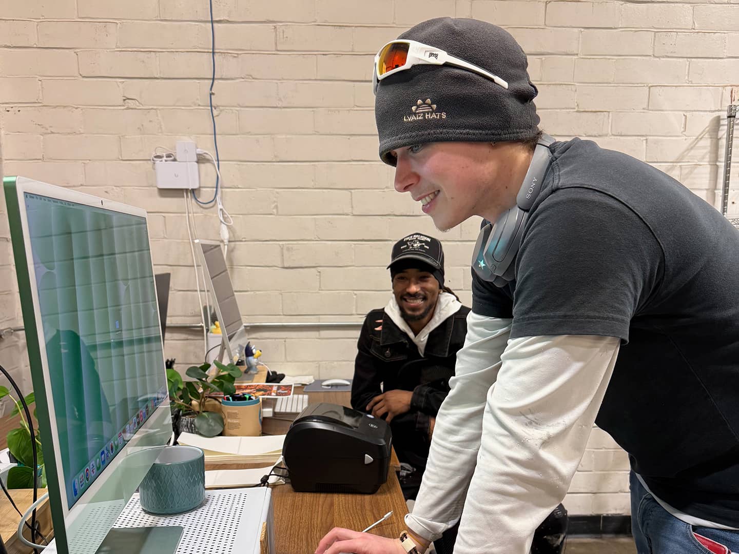 Two people talking while looking at iMac