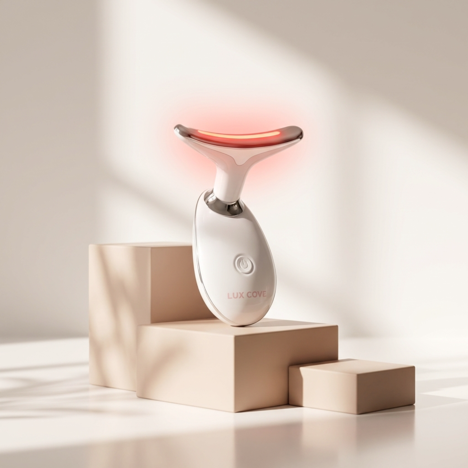 A white Lux Cove beauty device with a glowing red head, displayed on beige blocks.