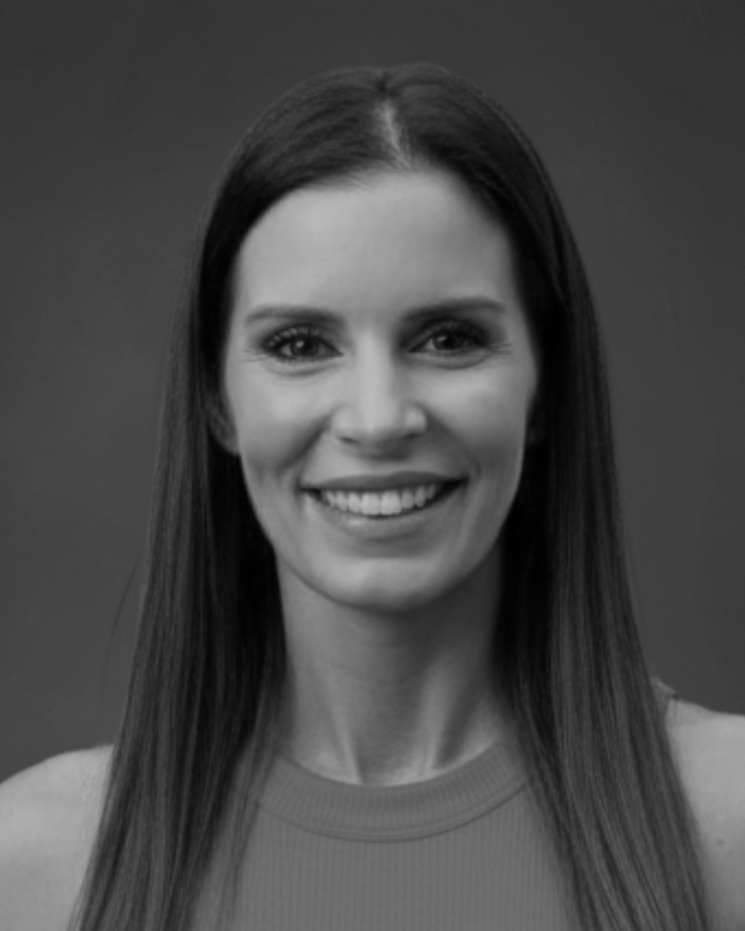 A black and white headshot of a woman with long, dark hair smiling at the camera.