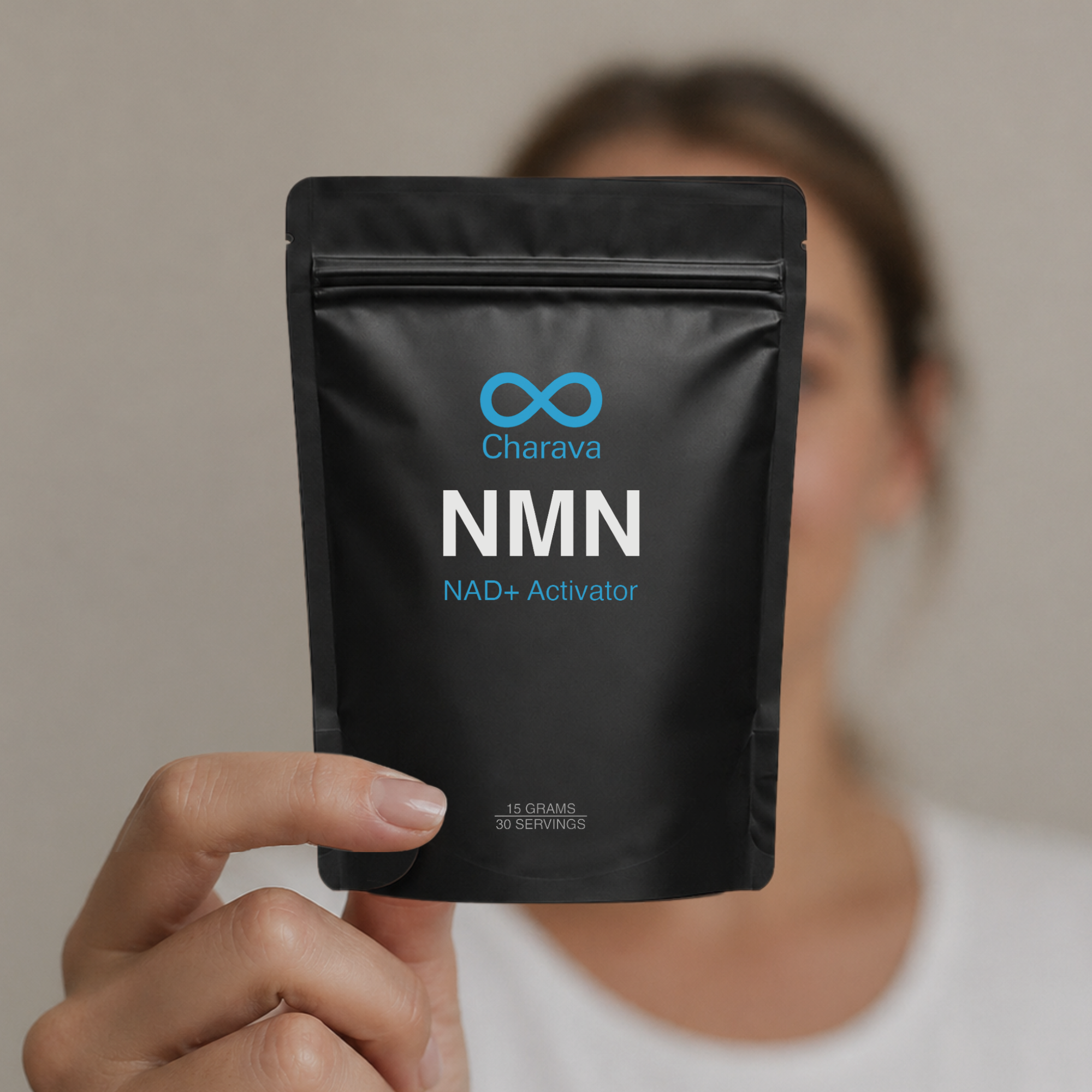 A person holds up a black pouch of Charava NMN NAD+ Activator against a plain background.