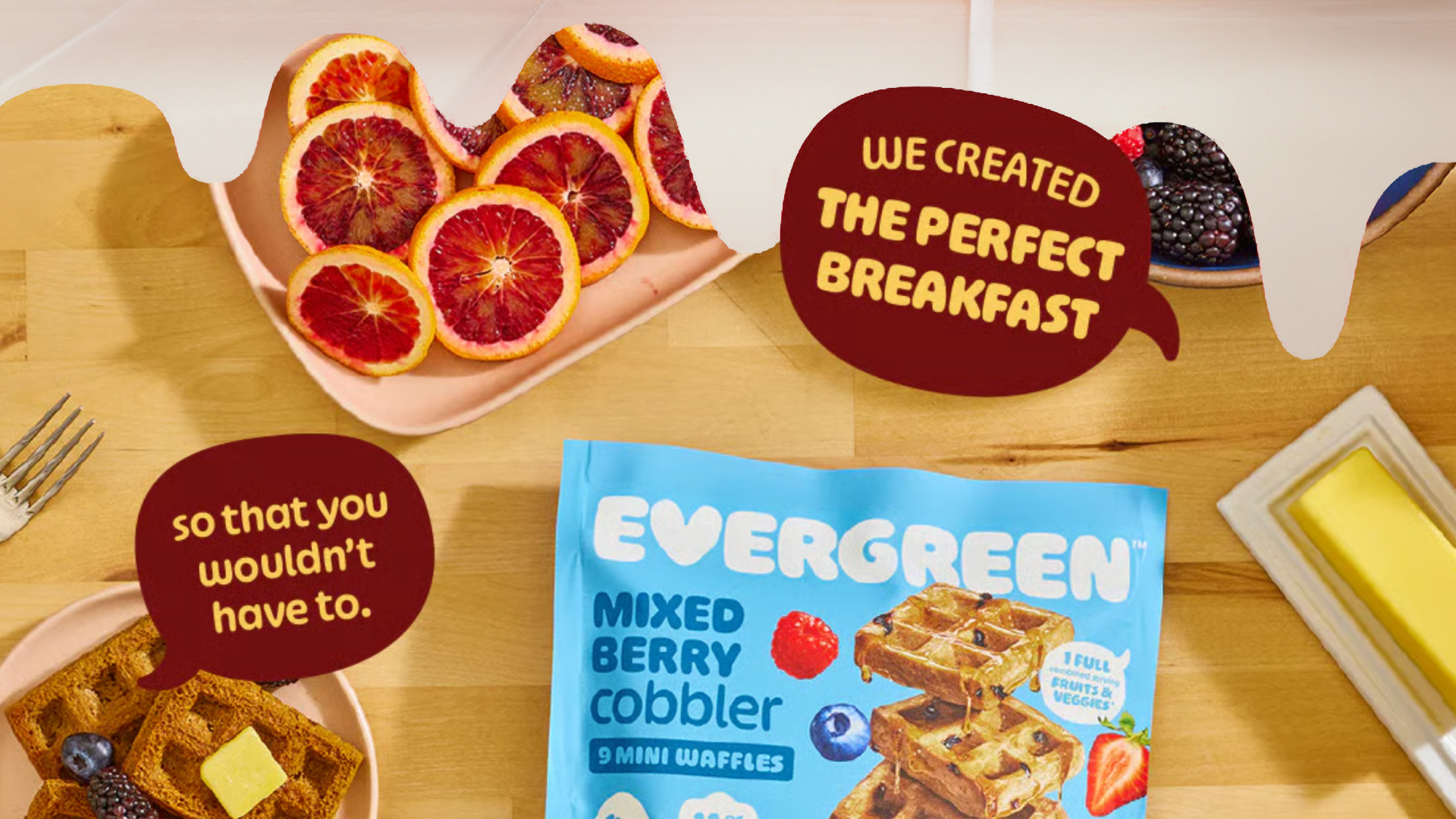 Assorted breakfast items including blood oranges, waffles, and mixed berry cobbler packet on a table.