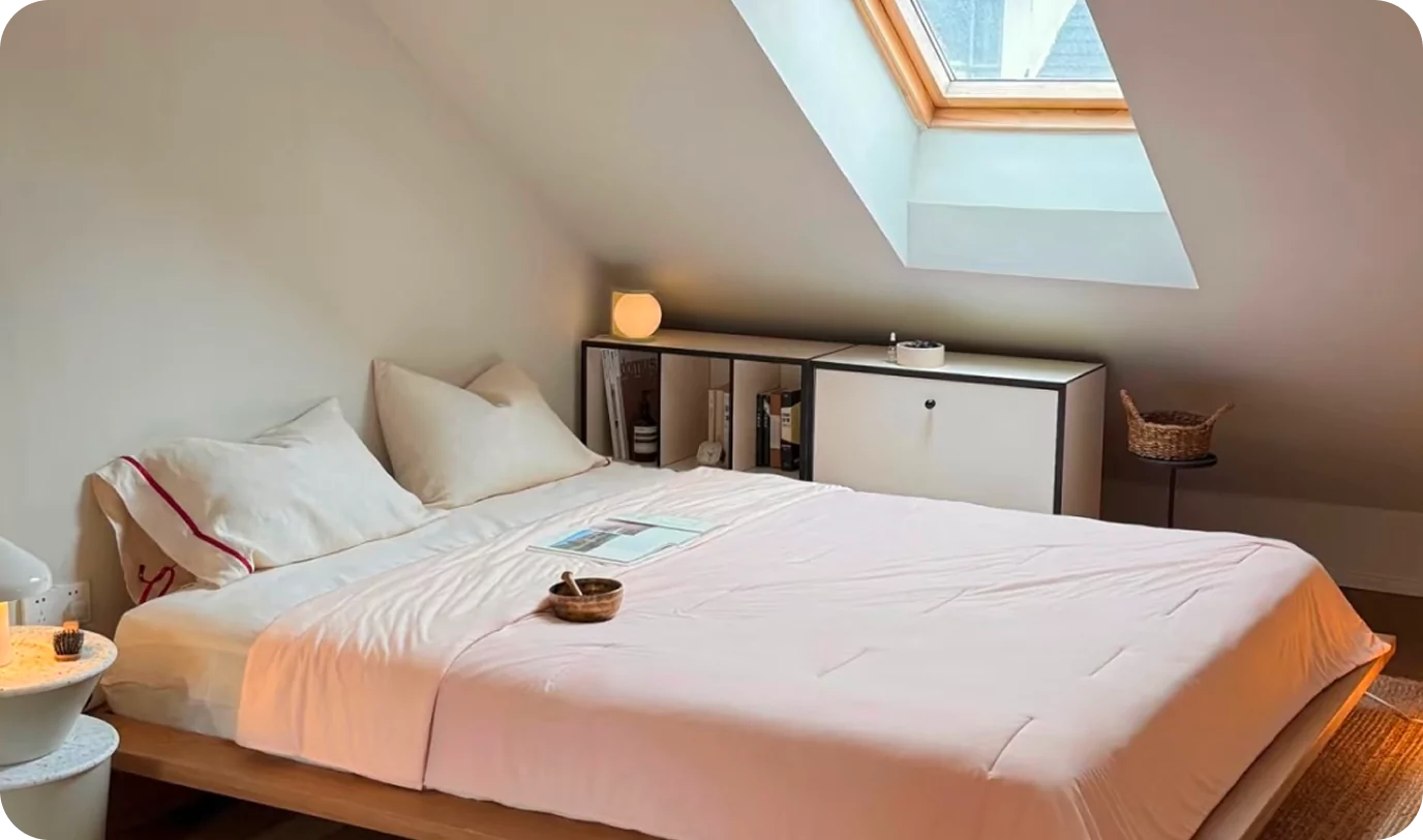 Cozy bedroom with a skylight, bed, and bedside table.