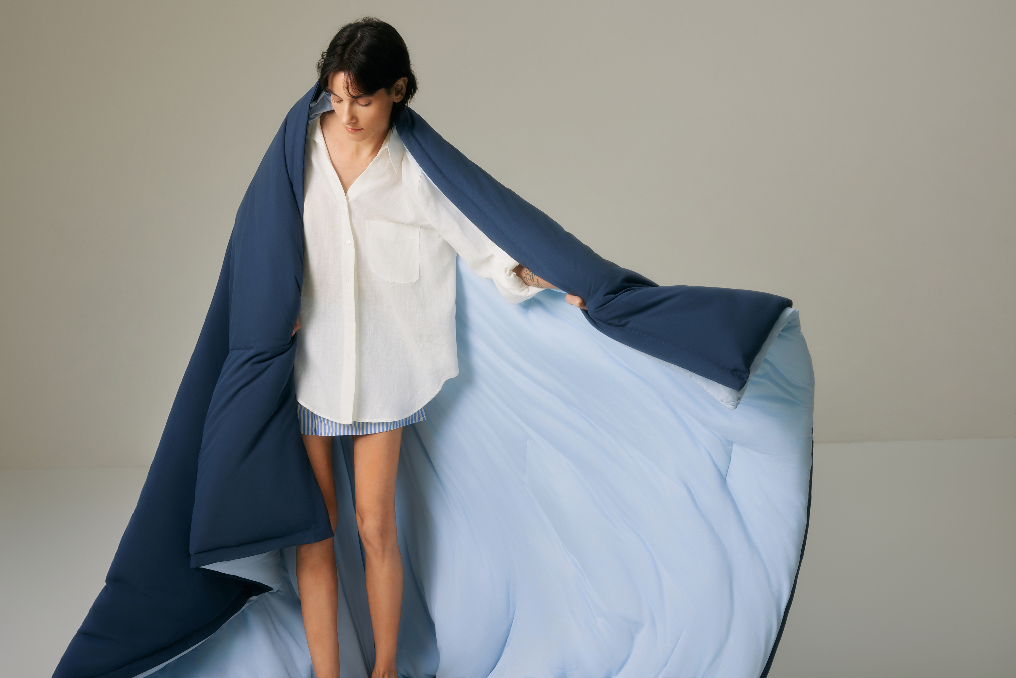 Person in white shirt wrapped in a flowing blue fabric.