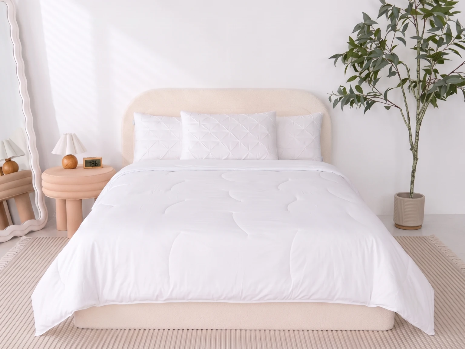 A bed with a white comforter and pillows in a brightly lit, contemporary bedroom.