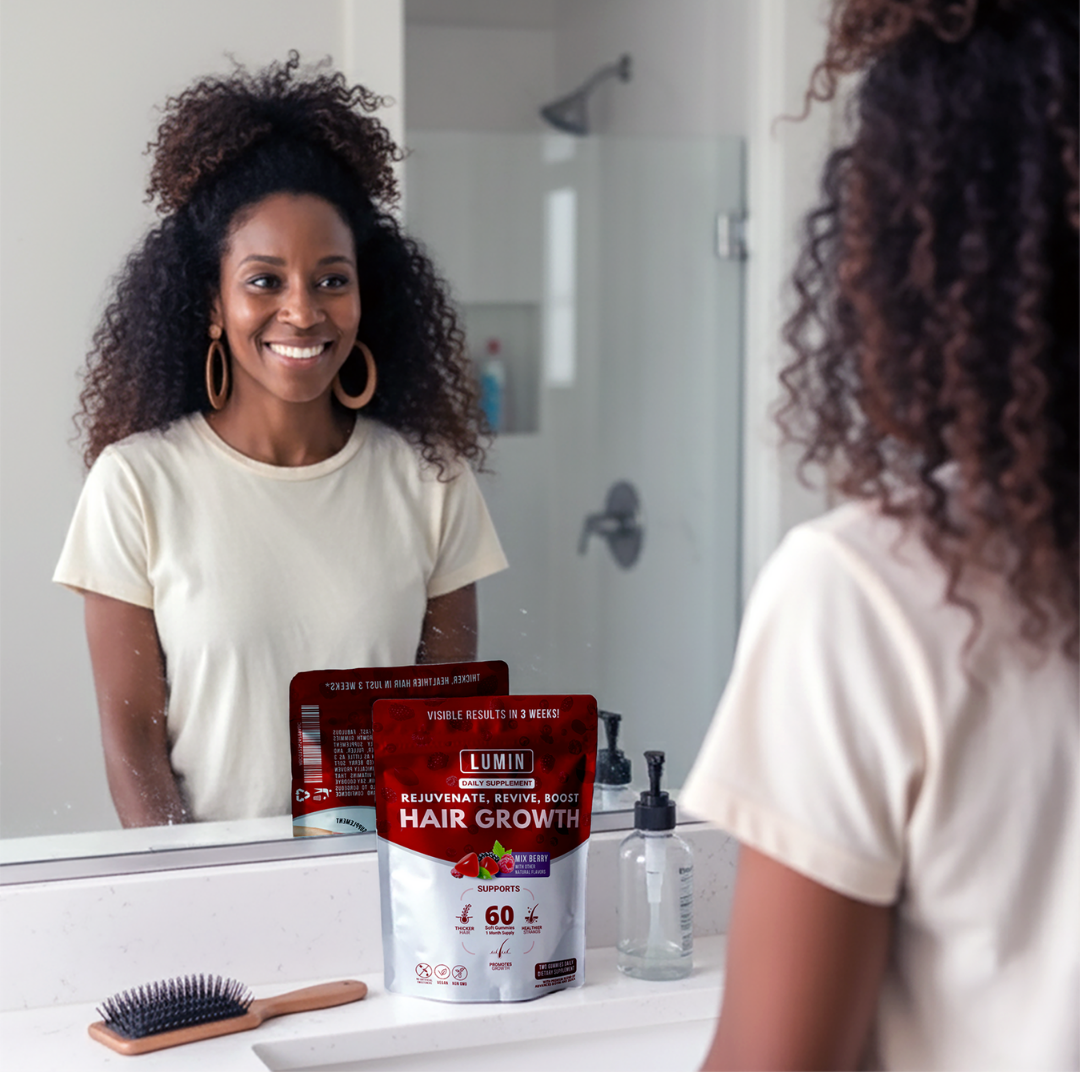 Woman smiling at mirror in bathroom with hair growth product on counter.
