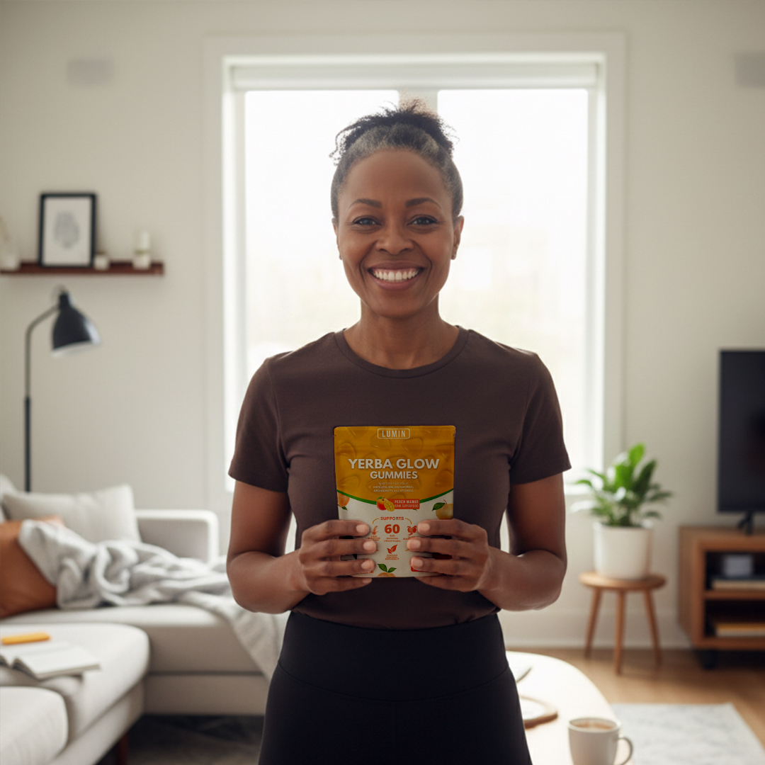 Person smiling and holding a package of Yerba Glow gummies in a living room.