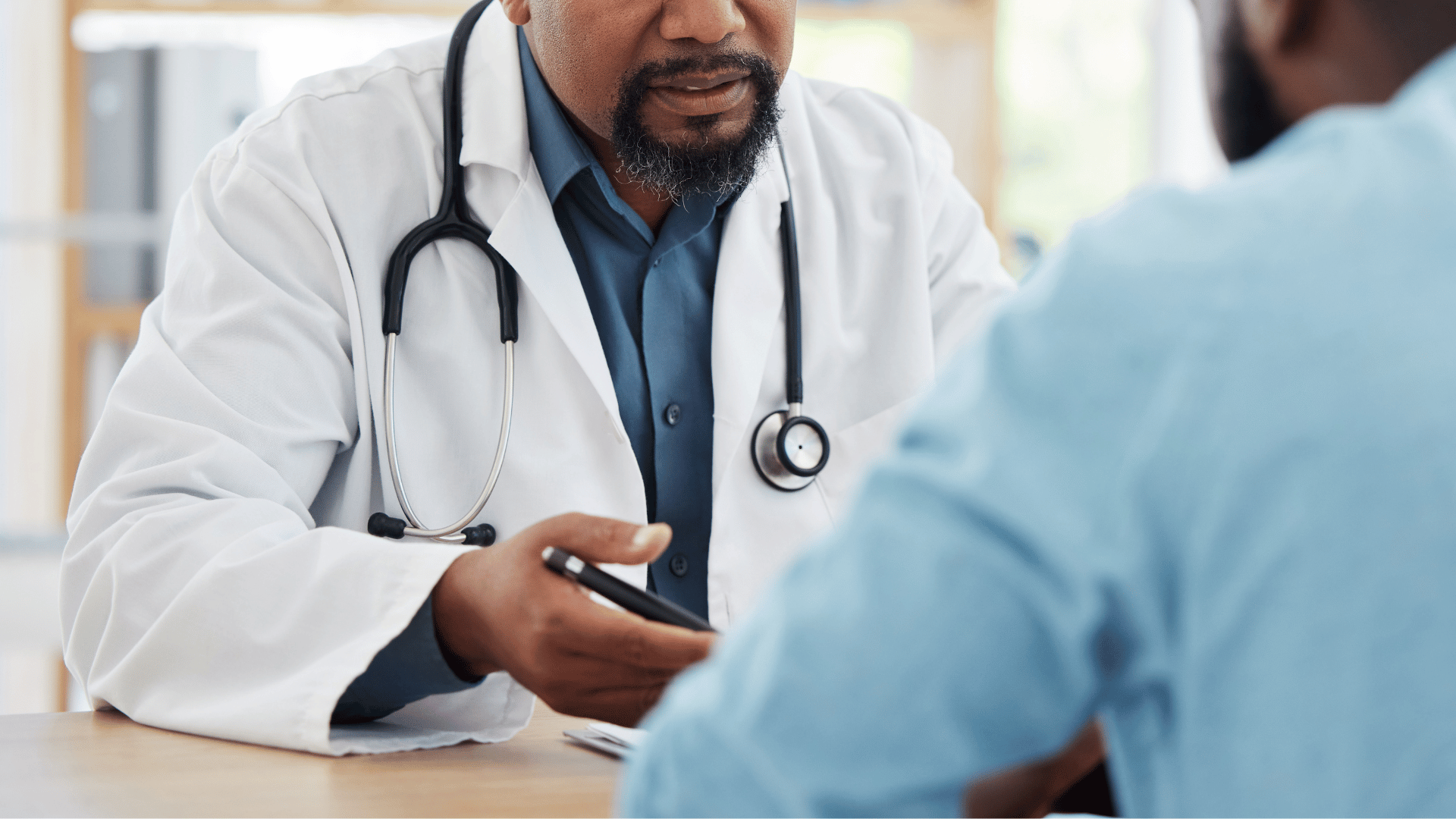 Doctor in white coat with stethoscope talking to a patient.