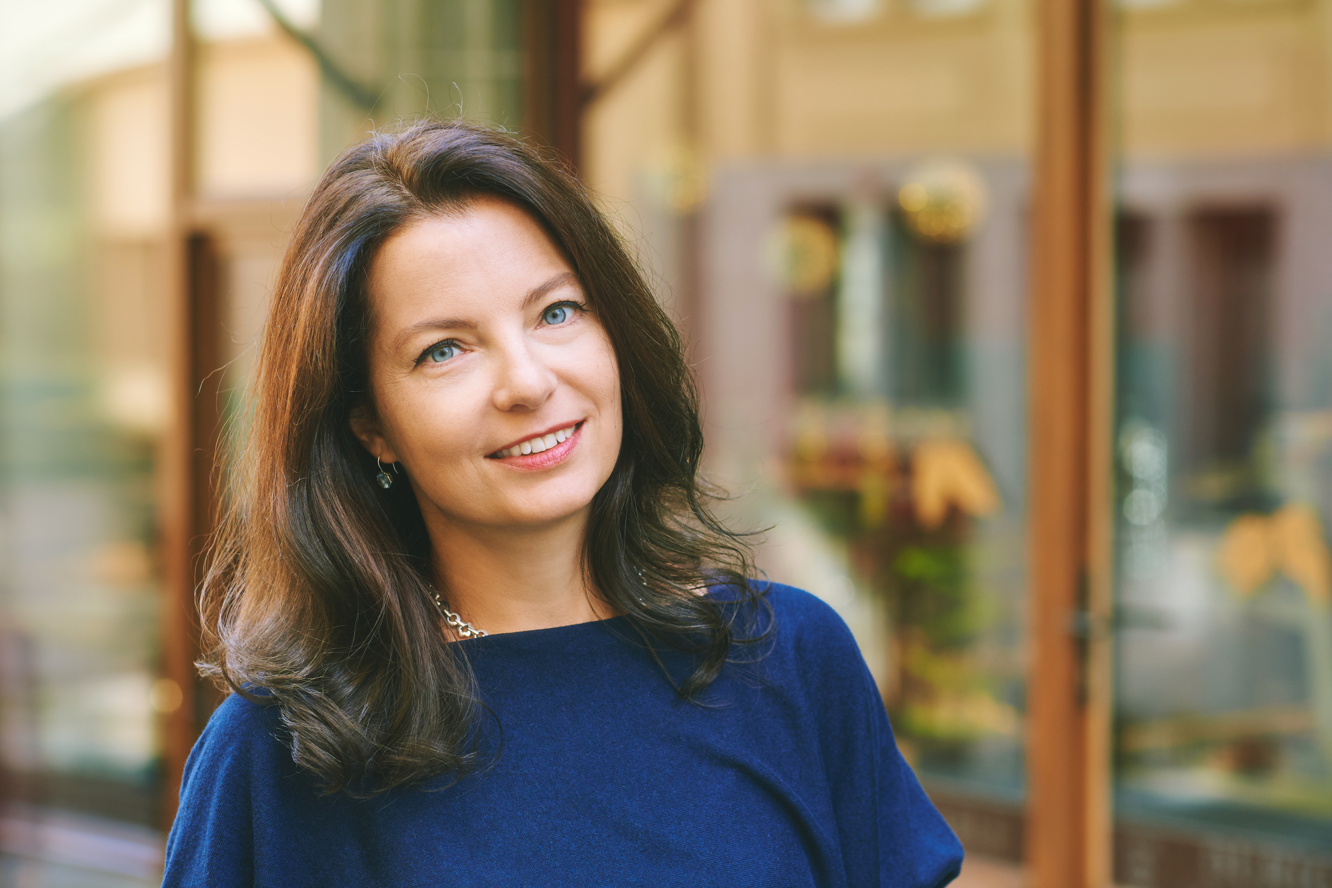 Woman with long brown hair smiling in an outdoor setting.