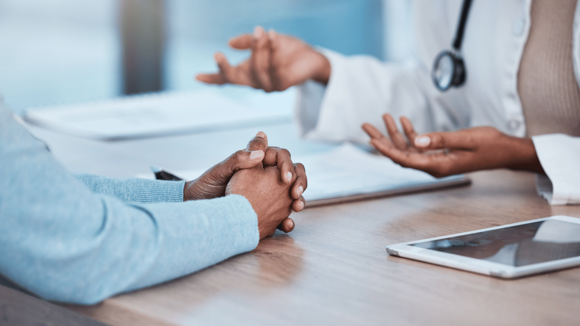 Two people having a discussion at a table, one wearing a stethoscope.