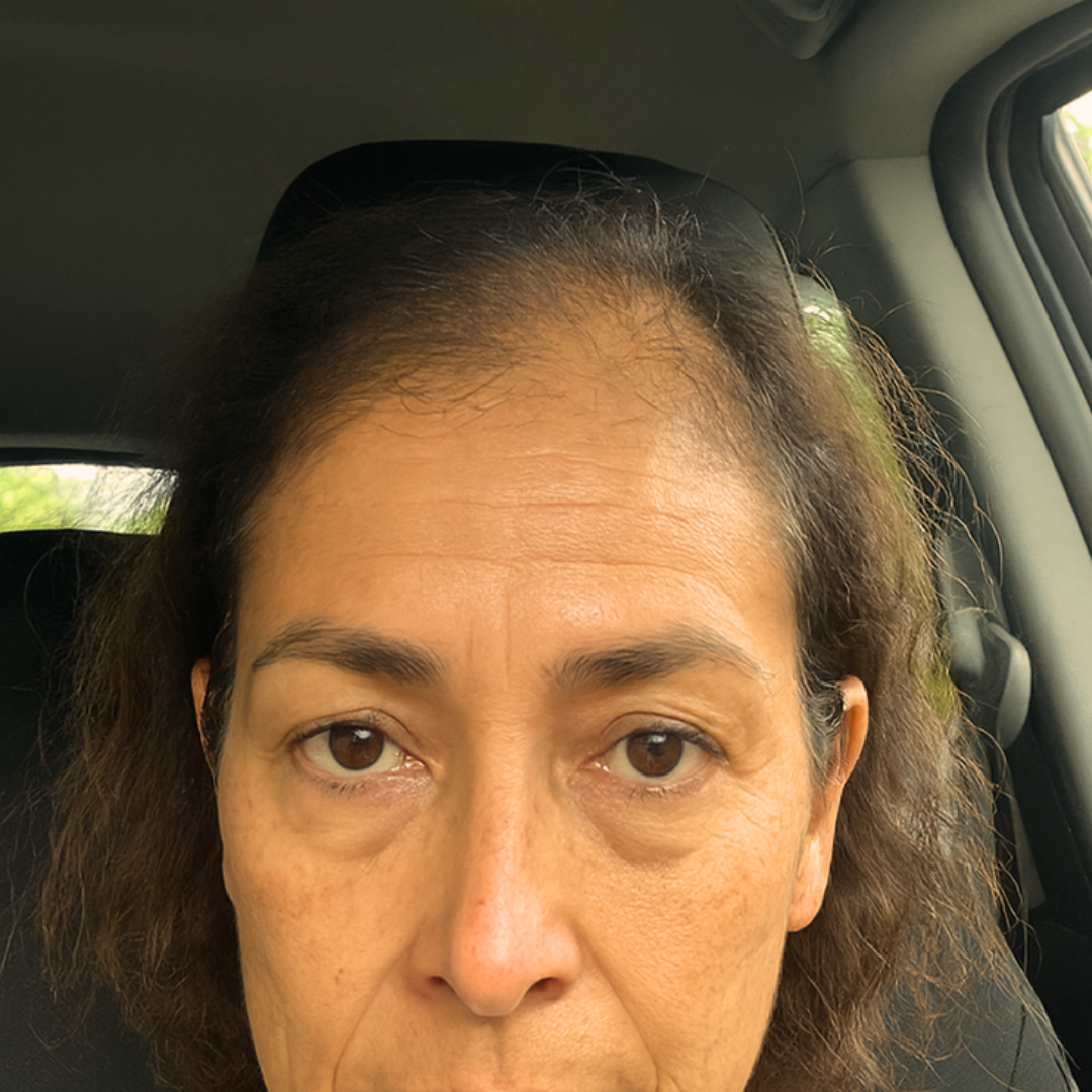 Person sitting in a car, looking directly at the camera.