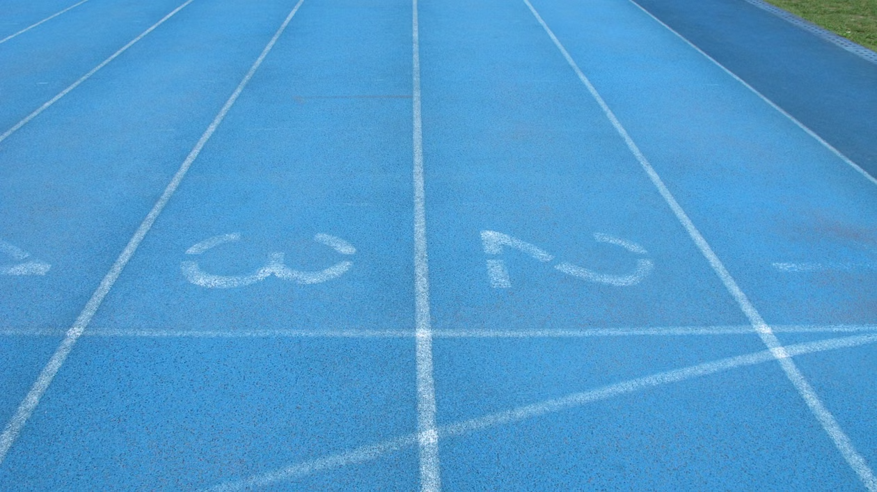 A low-angle, close-up view of a blue running track, showing the white lines for lanes 2 and 3.