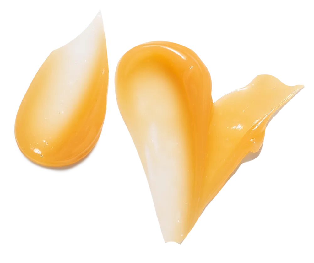 Two smears of a translucent, honey-colored, gel-like cosmetic product on a white background.