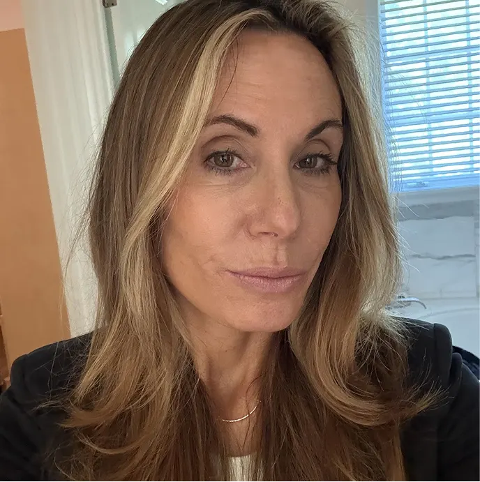 A headshot of a woman with long, highlighted blonde and brown hair looking at the camera.