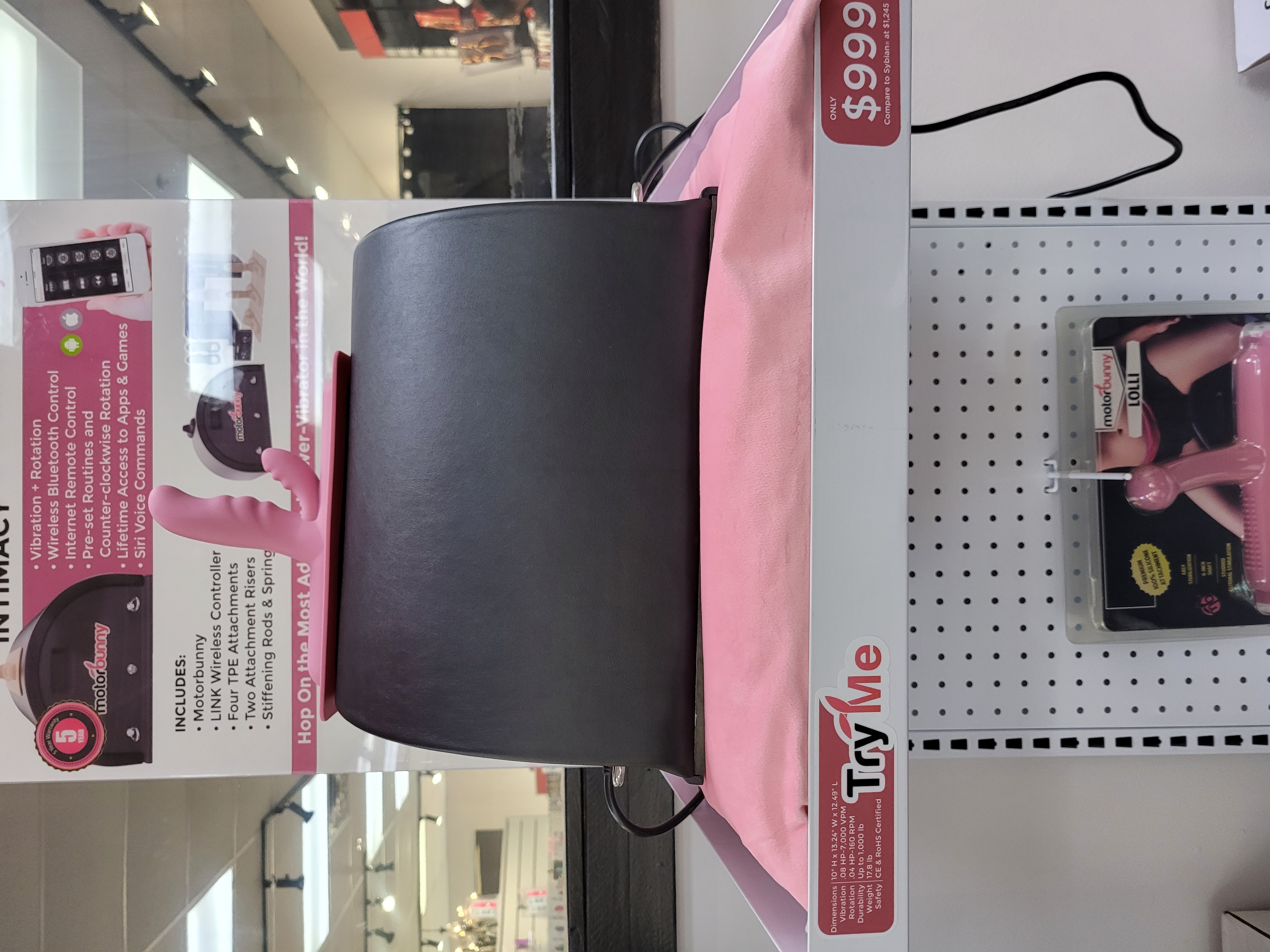 Display of a motorized adult product with pink attachments in a store.
