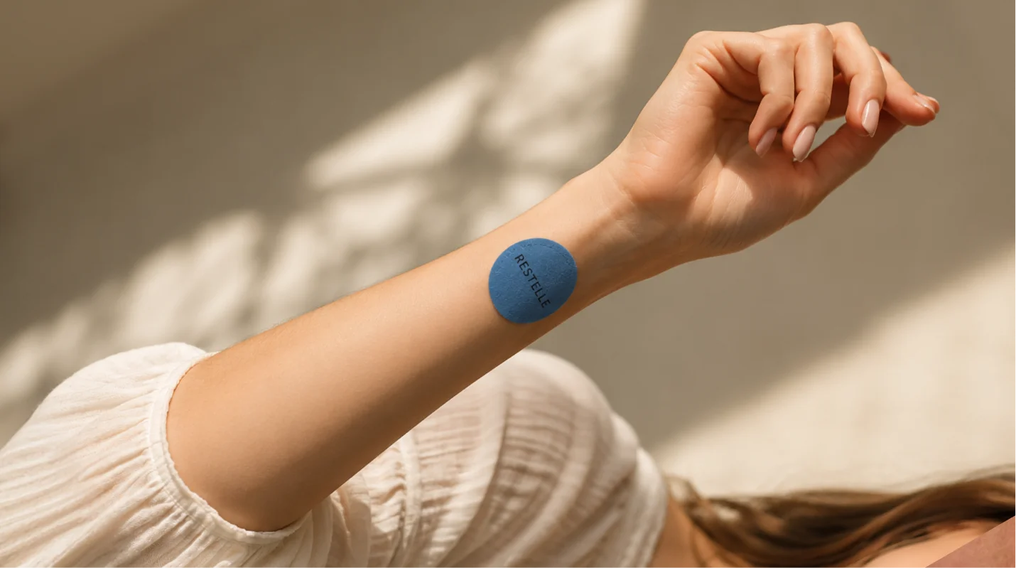 A close-up of a person's arm with a blue, circular patch that reads 'RESTELLE' on it.