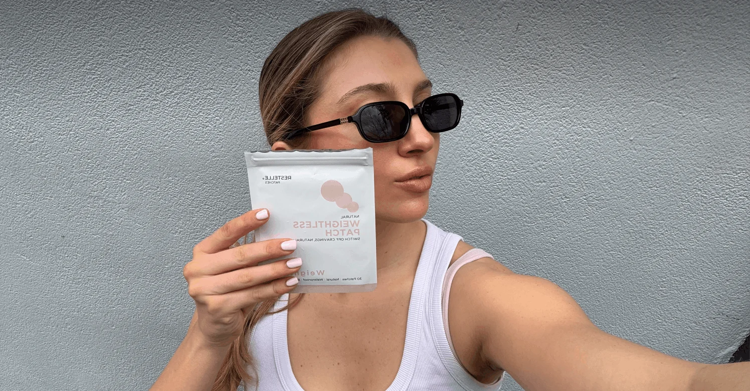 A woman in sunglasses and a white tank top holds a white packet labeled Natural Weightless Patch.