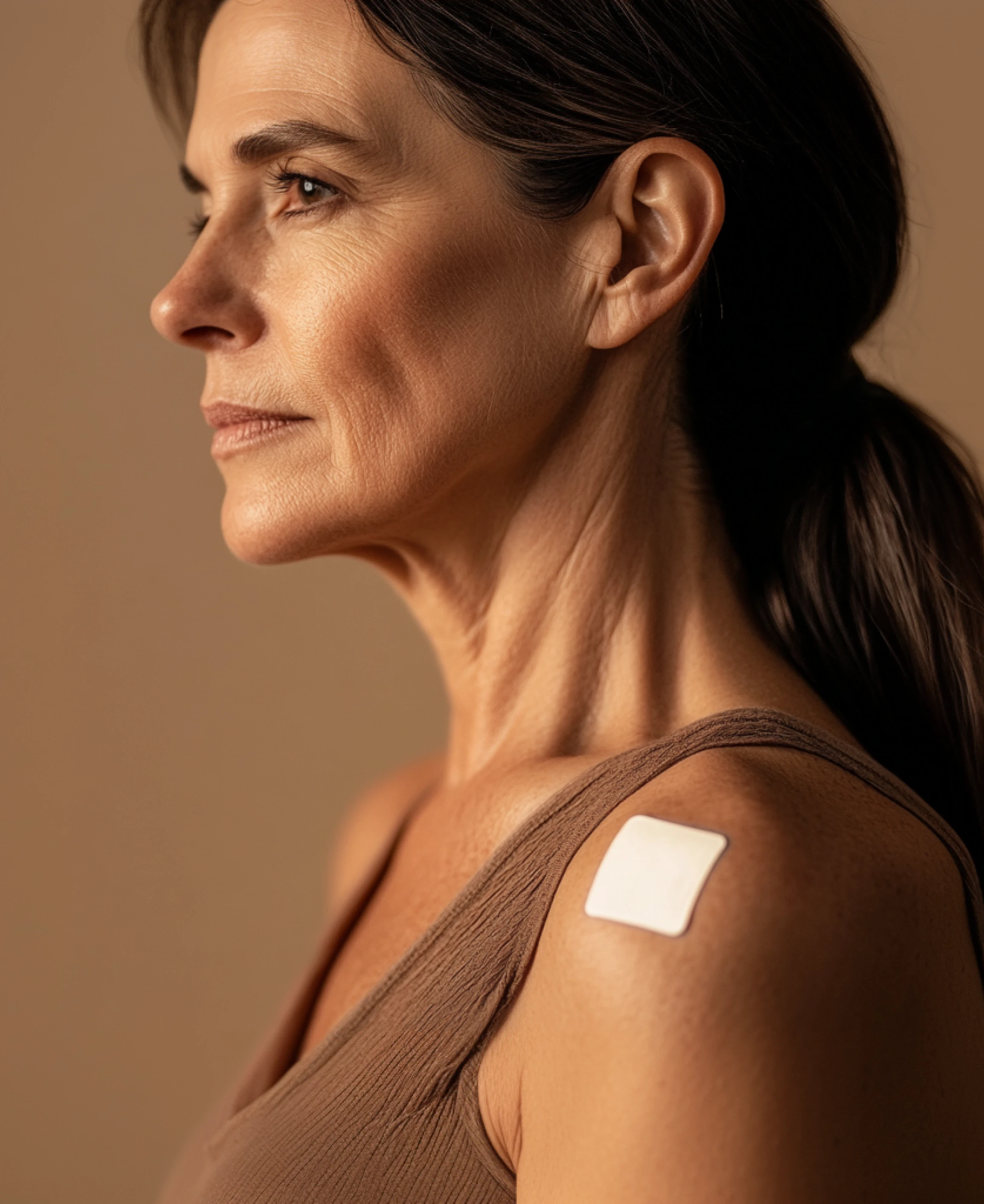 Woman with a patch on her shoulder, wearing a brown top.