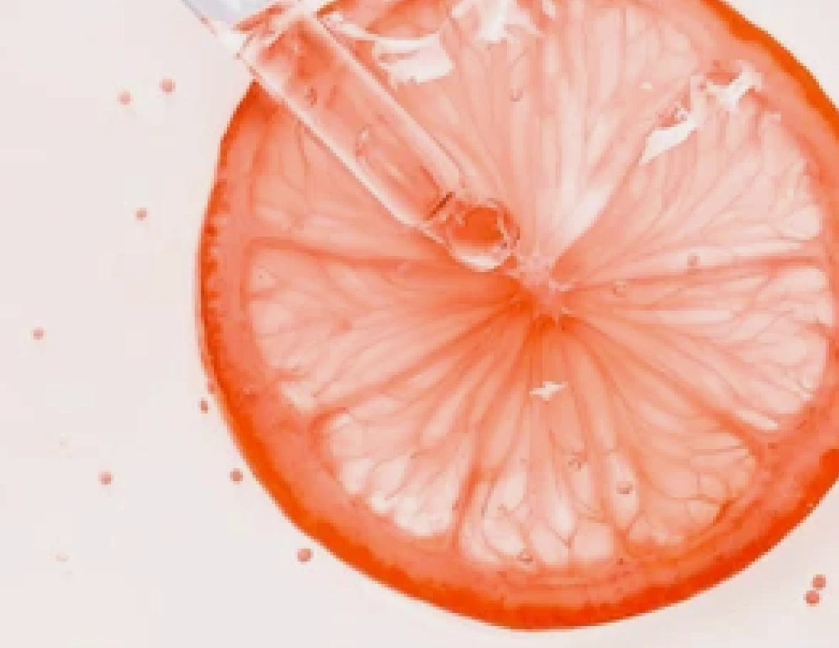Slice of grapefruit with a dropper above it.