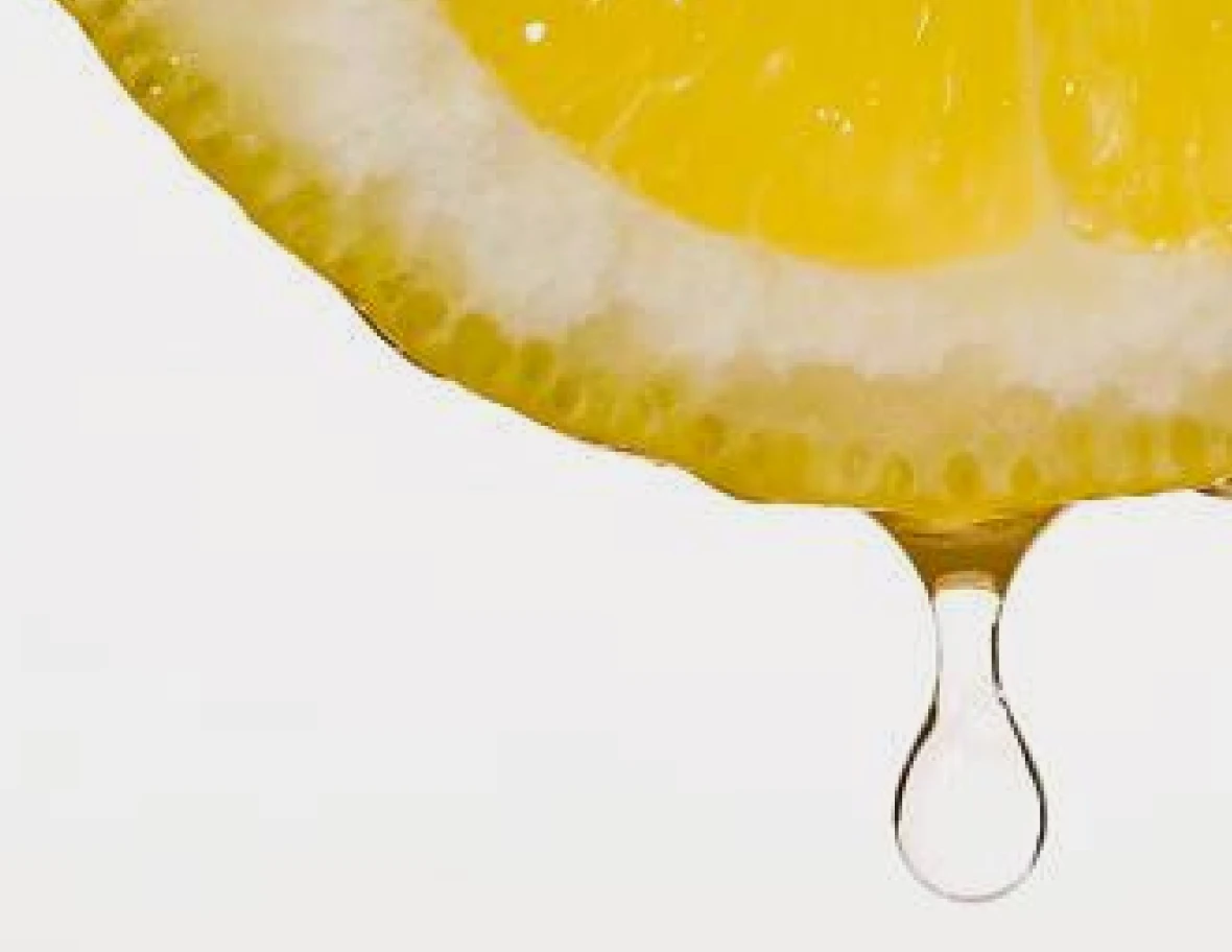 Close-up of a lemon slice with a droplet of juice falling.