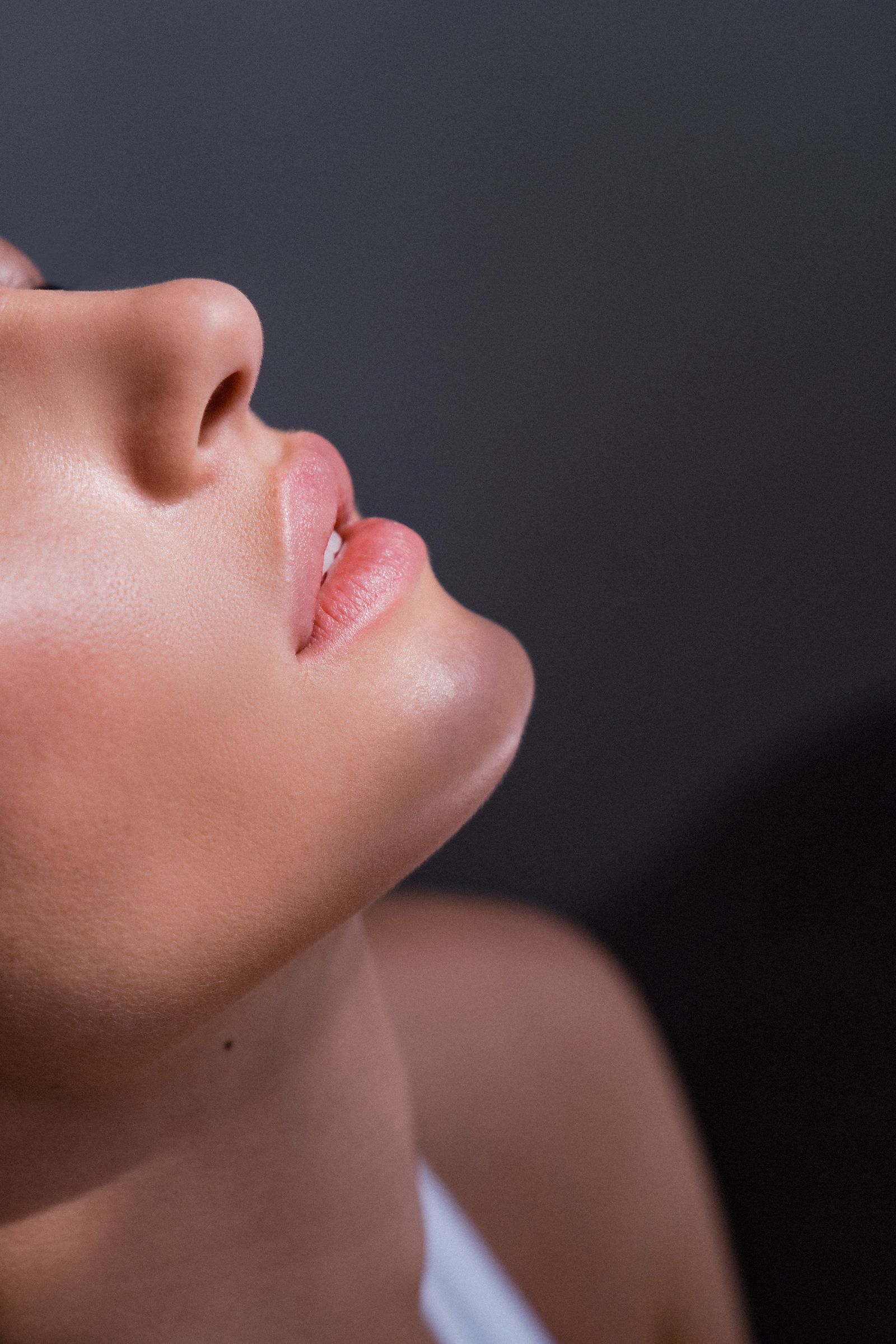 A close-up, low-angle profile of a woman's face, showing her nose, lips, and chin.