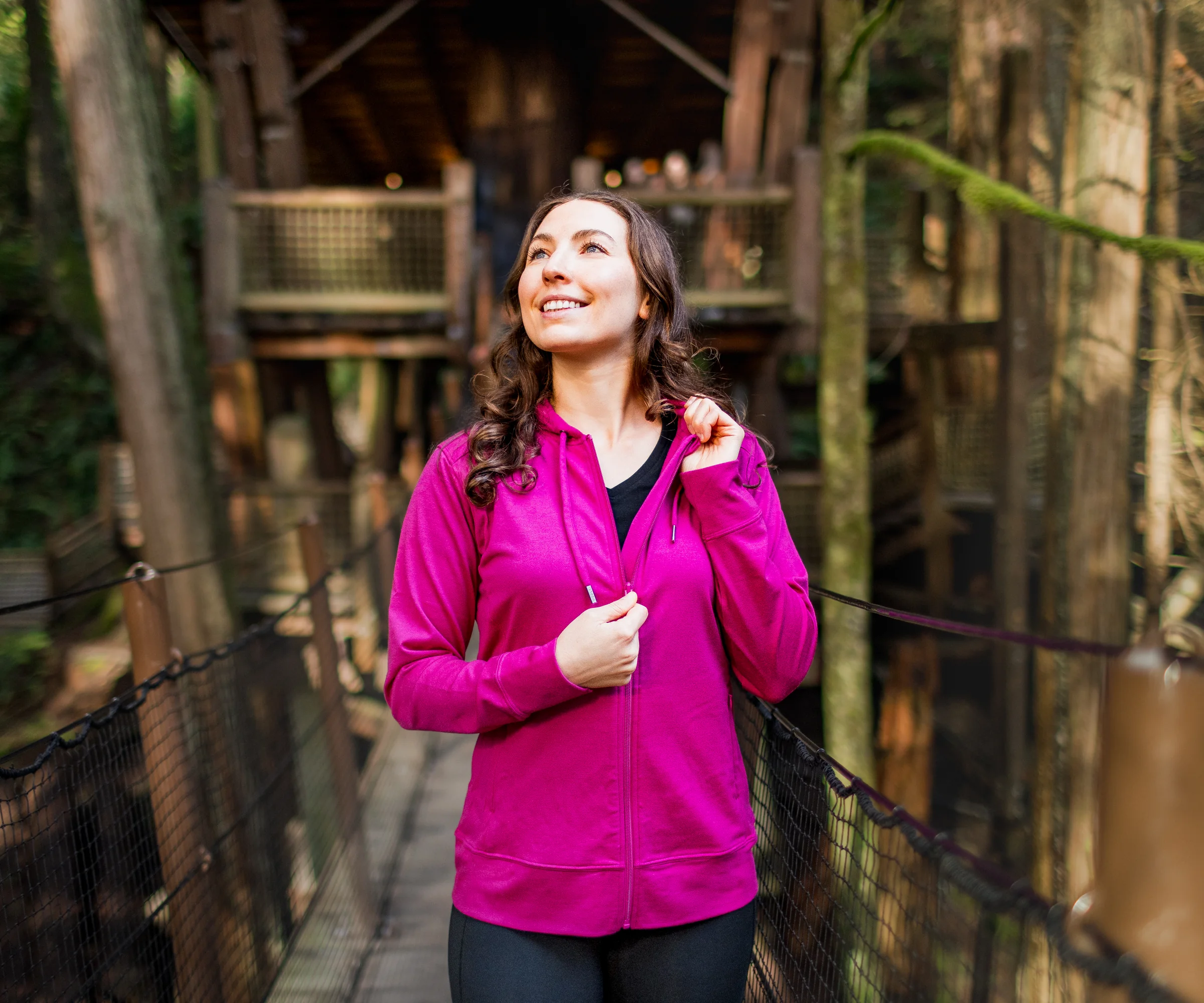 Woman wearing a pink Ryann Merino Hoodie on a forest suspension bridge