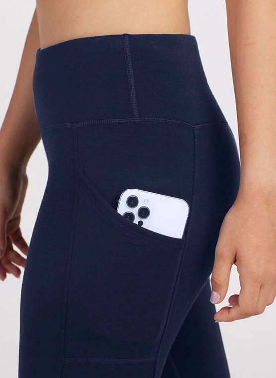 Close-up of navy blue leggings with a smartphone in the side pocket.