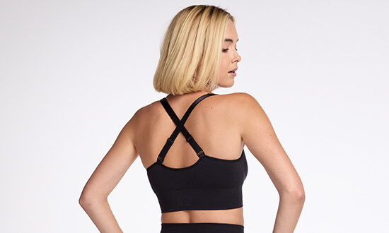 Person wearing a black sports bra with crossed straps, viewed from the back.