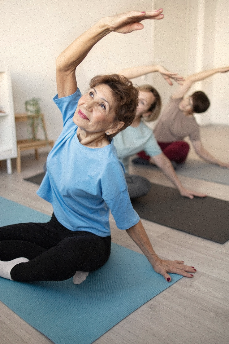 Three people doing seated yoga stretches on mats indoors.